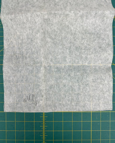 Paper pattern tissue with writing on it on top of a green cutting mat.