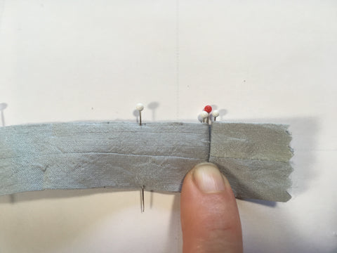 The second fold of the box-pleat matching white pin to center red pin.