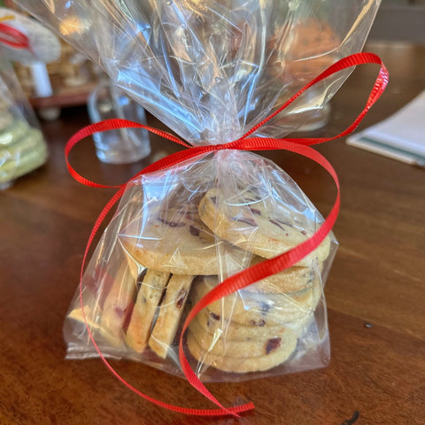 Cookies in a clear cellophane bag on a wooden table, tied with a red ribbon.