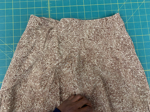 beige and brown floral fabric yoke topstitched on the top front skirt, on a green cutting mat.