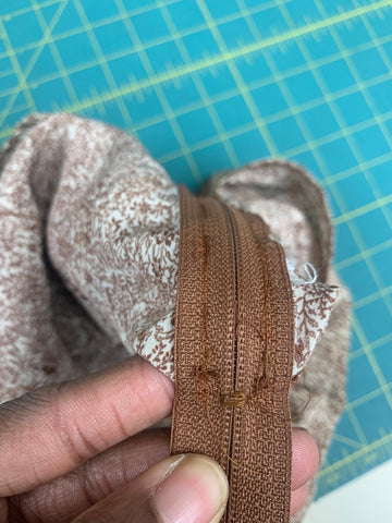 close up of large brown zig-zag stitches on a brown zipper to make a zipper stop.