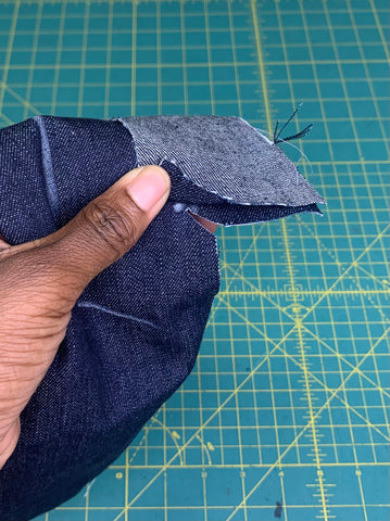 close up of clipped to dot on a dark blue denim fabric on a green cutting mat.