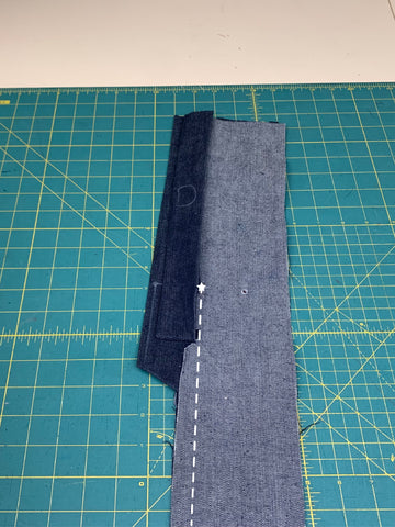left and right sides of skirt back pieces sewn together with the placket and facing. illustrated dashed line with a star on top shows where it was sew together from the hem up to the star, on a green cutting mat.