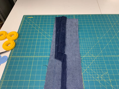 seam pressed open of the back skirt peices with the placket and facing sewn together at star to hem on a green cutting mat.