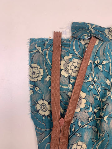 Placed right side of the center of the zipper teeth onto the right side of the facing D. On teal and taupe floral fabric.