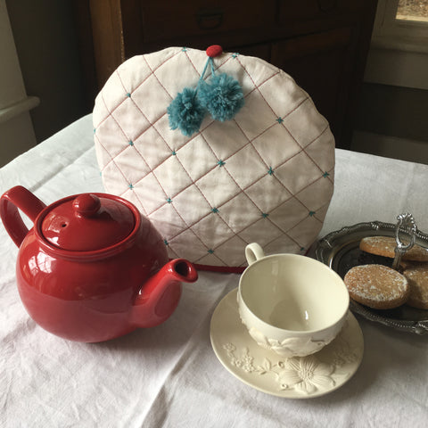 Photo of tea cozy and pot and cups on table