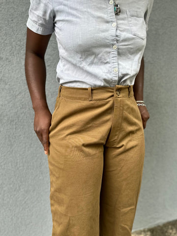 Close up of olive khaki sanded twill pants with African woman wearing them with thumbs in pockets.