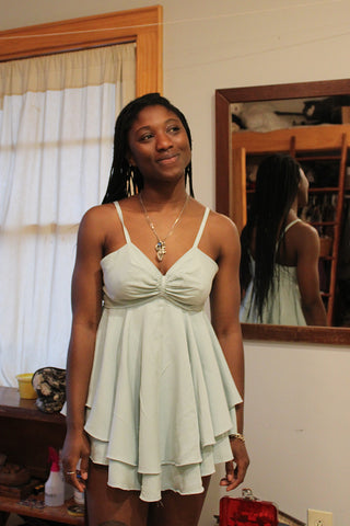 Smiling African American model wearing garment in a room with her back reflected in the mirror in the background.