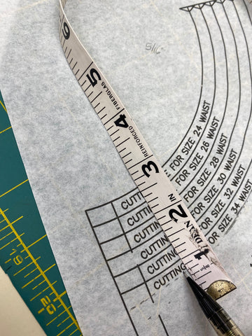 paper pattern with measuring tape and pencil to measure waist.