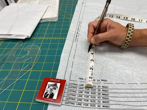 paper sewing pattern with pencil and measuring tape being marked.