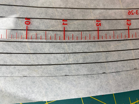paper sewing pattern with curved plastic clear ruler on a green mat