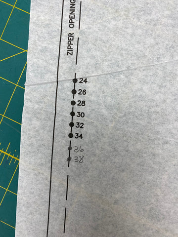 paper sewing pattern with markings on a green mat.