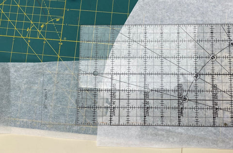 clear plastic ruler on paper sewing pattern on green mat