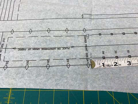 White paper pattern with ruler and pencil marking new notches.