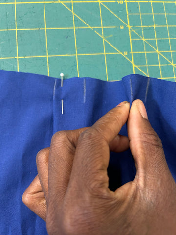 A hand pinching the pleat together in the center.