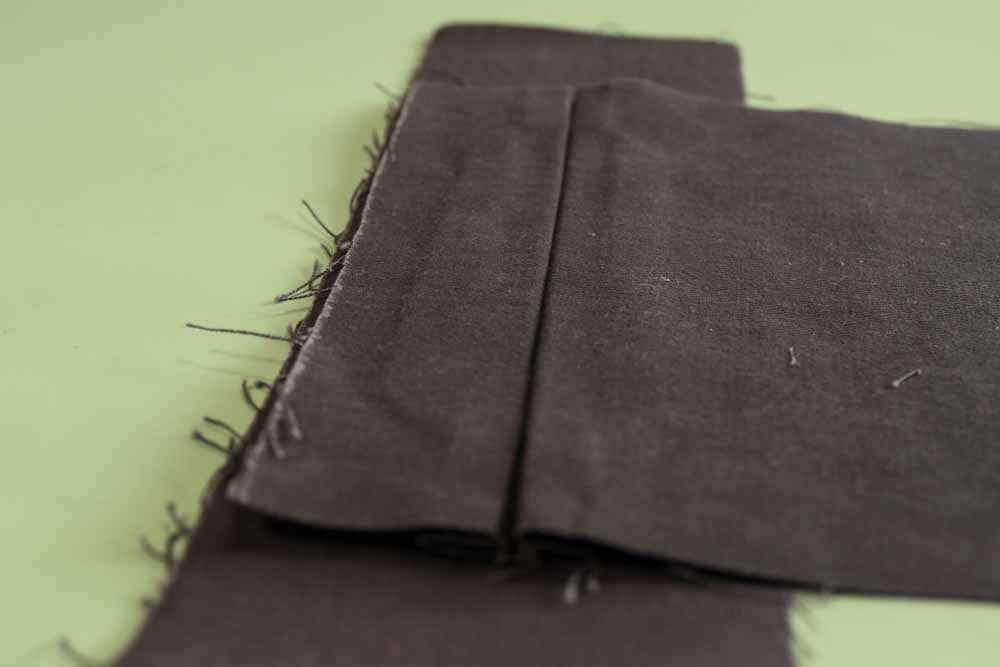 View of the welt pocket pleats folded on the backside of the waistband. 