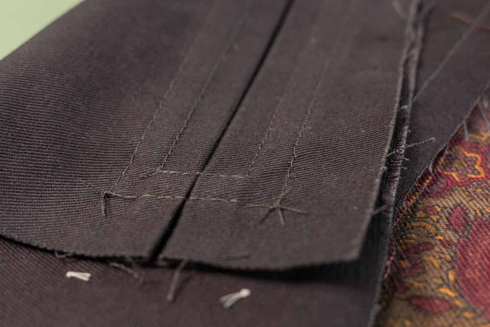 The corner threads of the top stitching tied off on the backside of the pocket opening.