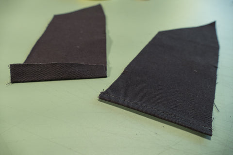 On the left, the top edge of the Center Back Eyelet Facing under 1/2" (13cm). On the right the edge turned under 1/4" and stitched close to the edge to finish.