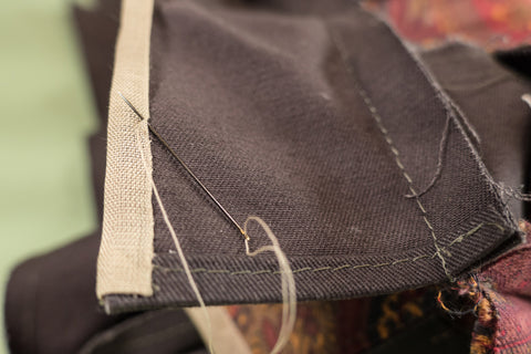 Whip stitching the seam binding to cover the raw edge.