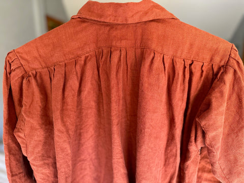 close up of back pleats on burnt orange linen dress