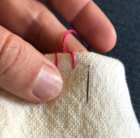 blanket stitch, first stitch, red thread on white cotton