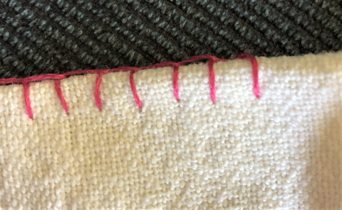 blanket stitch for embroidering edge of fabrics - red on white fabric.