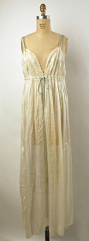 cream silk nightgown on dress form.  Gown is long, sleeveless and has a deep v  with blue ribbon at empire waist.