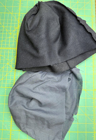 Navy hat outer and lining pieces on green cutting mat.