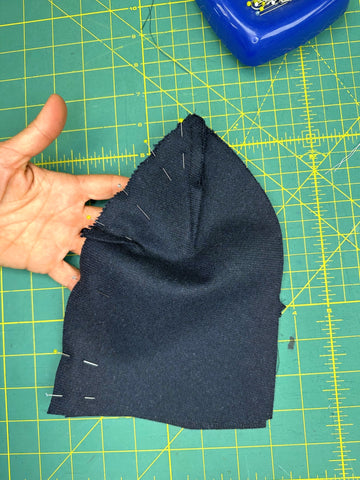 navy wool hat piece with sewn darts on a green cutting mat