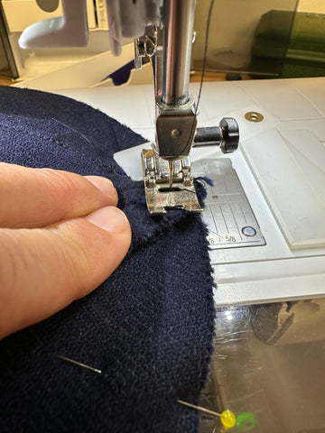 sewing navy wool in a machine with a plastic seam jumper.