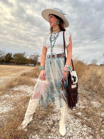 woman wearing a shear blue skirt with cowboy boys and a hat.