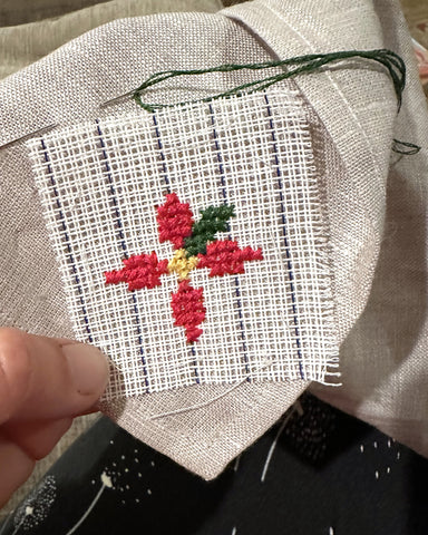 poinsetta embroidery beginning with cross stitch on a napkin with waste canvas.