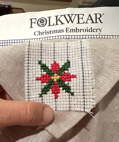 poinsetta embroidery beginning with cross stitch on a napkin with waste canvas.