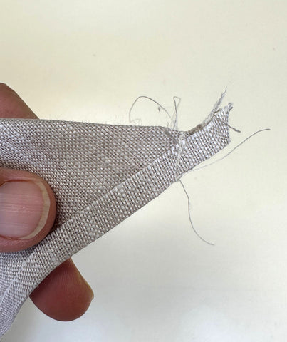 Grey linen napkin sewn together at corner.