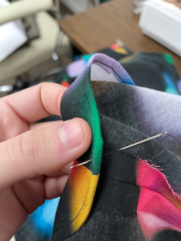 Tacking down the neck facing to the seam allowance of the shoulder seam