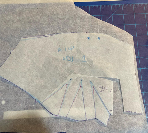 A pattern piece that has been cut into and moved to adjust the fit