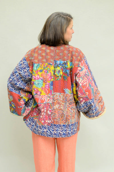 back of kantha jacket. woman has one hand on her hip and is looking over right shoulder.