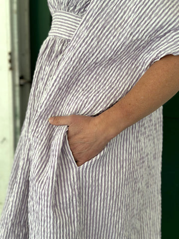 close up of hand in the pocket of a purple and white striped kaftan