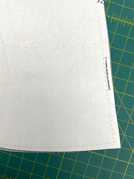 white pattern pieces on a green cutting mat with markings at 8" from the cutting line.