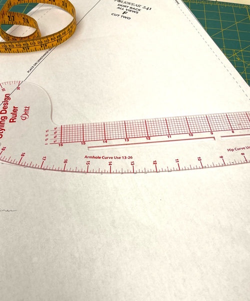 Clear plastic curved ruler on a white paper pattern piece.