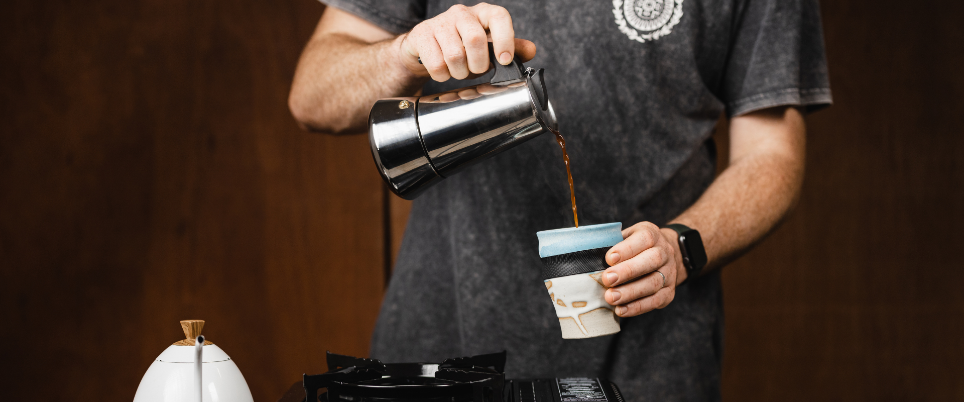 Person pouring coffee into a ceramic mug