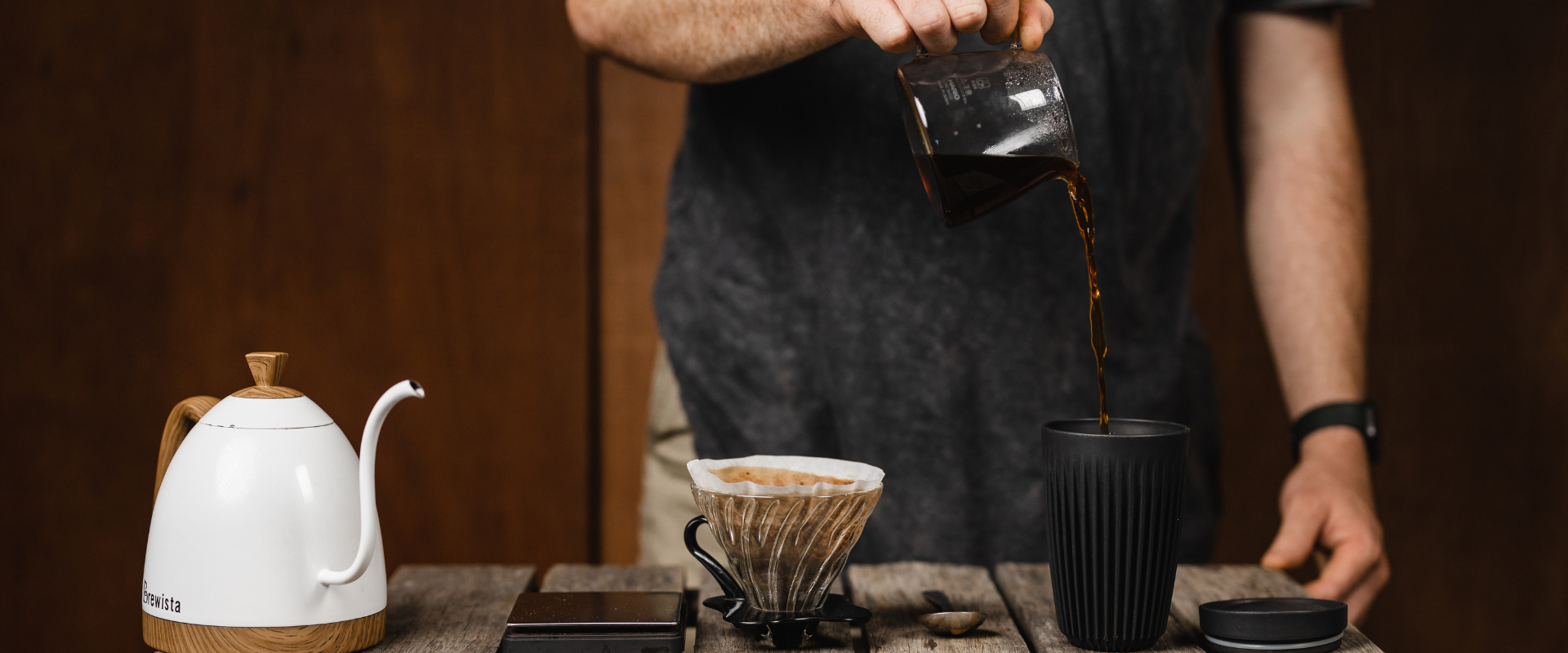 Person pouring coffee from hario server into huskee cup