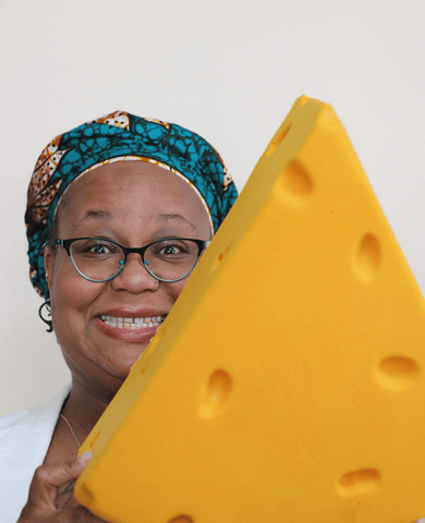 cheese culture coalition board member agela abdullah with a big fake piece of cheese