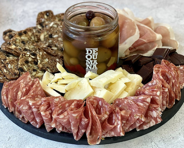 mixed olives in a jar with charcuterie and cheddar