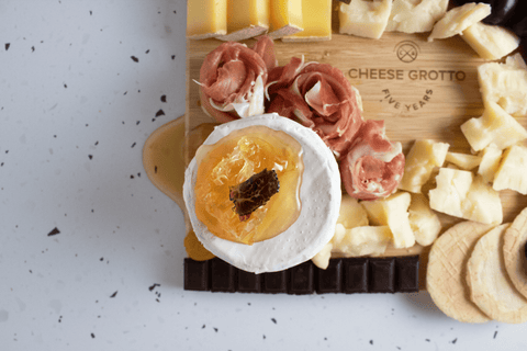 french camembert cheese on board with honey, truffle, charcuterie, and crackers