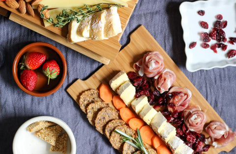 overhead view of bamboo cheese board with charcuterie, fruit, and crackers