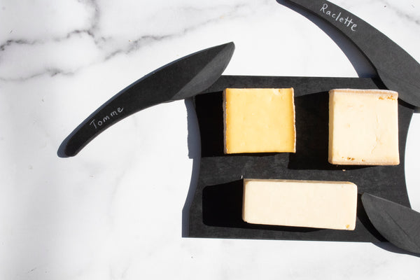 black cheese board and cheese knives