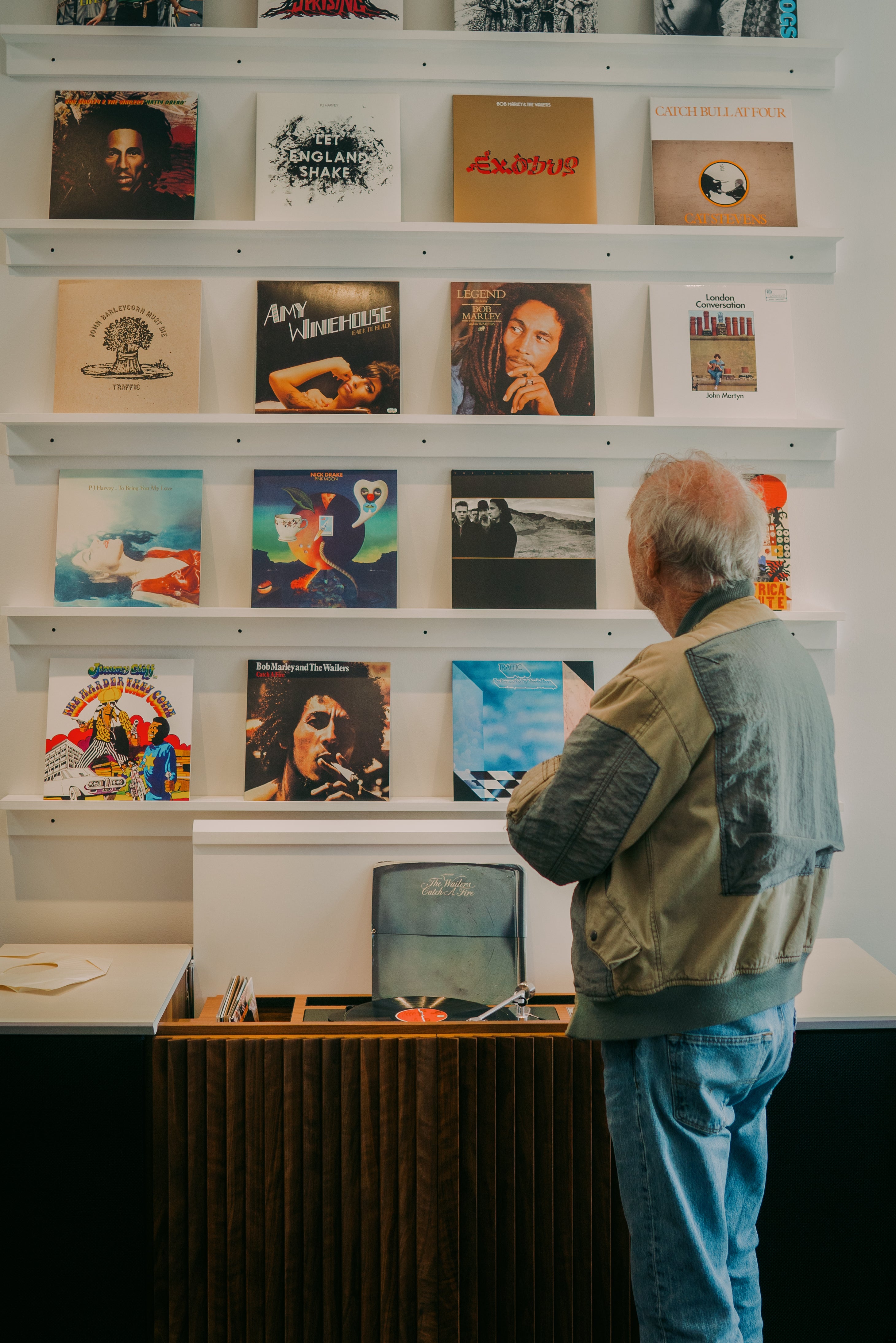 Chris Blackwell looking at a wall filled with albums from Island Records