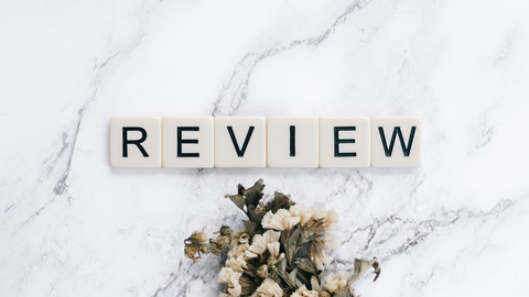 Scrabble tiles spelling out REVIEW on marble table with small white flowers