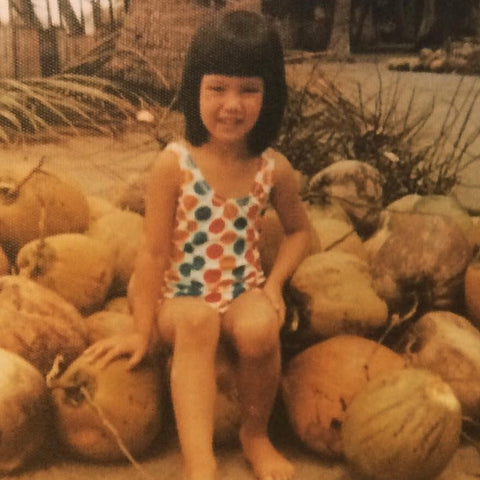 Chantal sitting on a bunch of coconuts